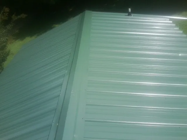 New green metal panels meeting at the ridge of a roof — Flat Roof Repair work by our crew in Pine